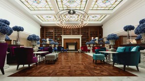 A spacious lobby with a high ceiling, a central fireplace, and a large stained glass skylight. - Astor Garden Hotel (Varna)