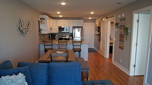 A modern kitchen with white cabinets, stainless steel appliances, and a dining area with a wooden table and chairs.