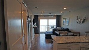 A spacious kitchen with a large island, a dining area with a table and chairs, and a balcony with a view.