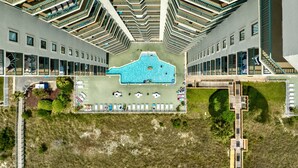 A modern hotel with a central swimming pool, multiple balconies, and a unique architectural design.