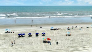 A beach with people, umbrellas, and a clear sky.