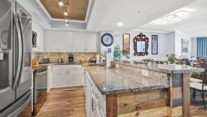 A modern kitchen with white cabinets, a granite countertop, and a wooden accent wall.