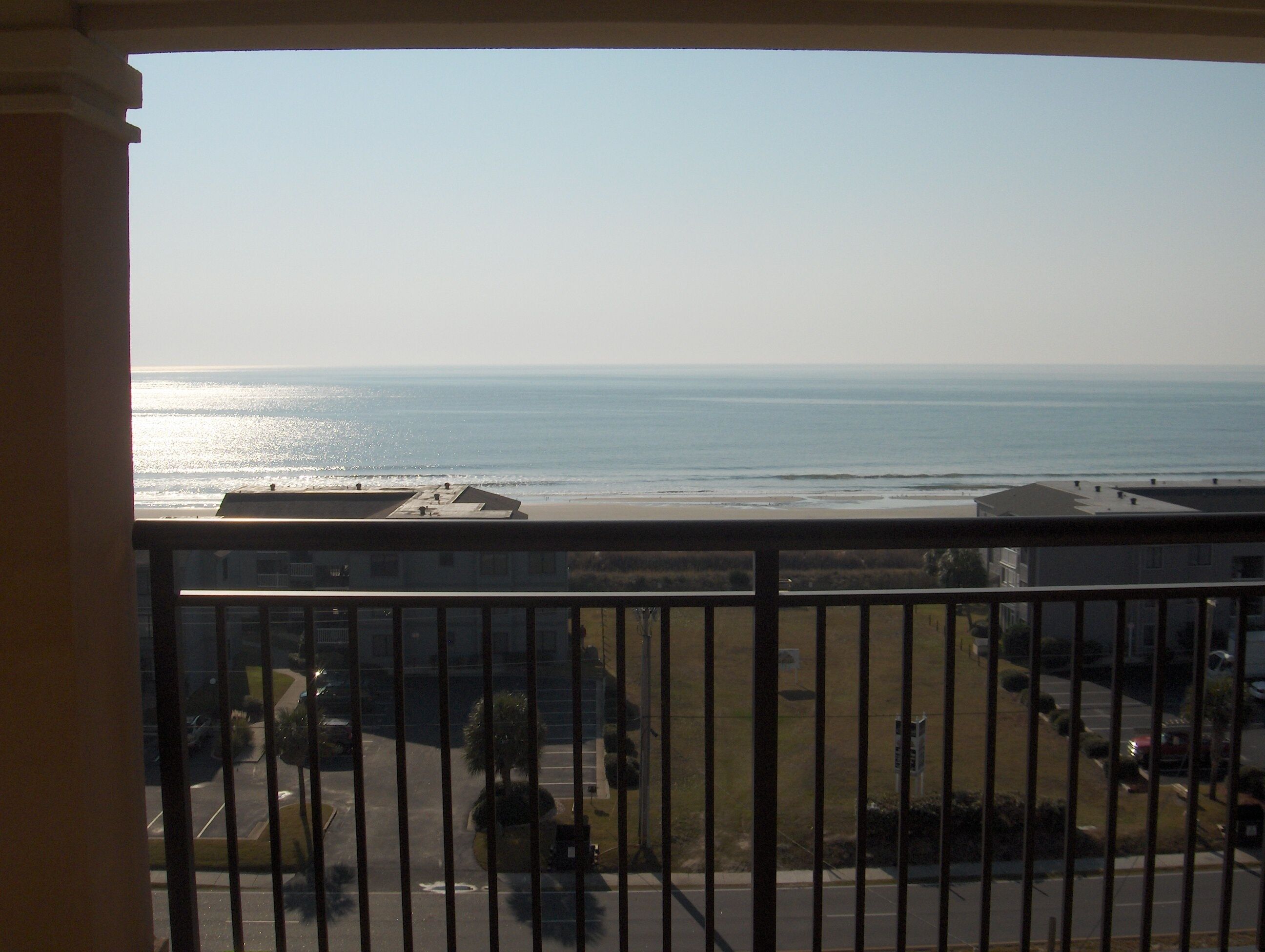 A balcony with a view of the beach and ocean.
