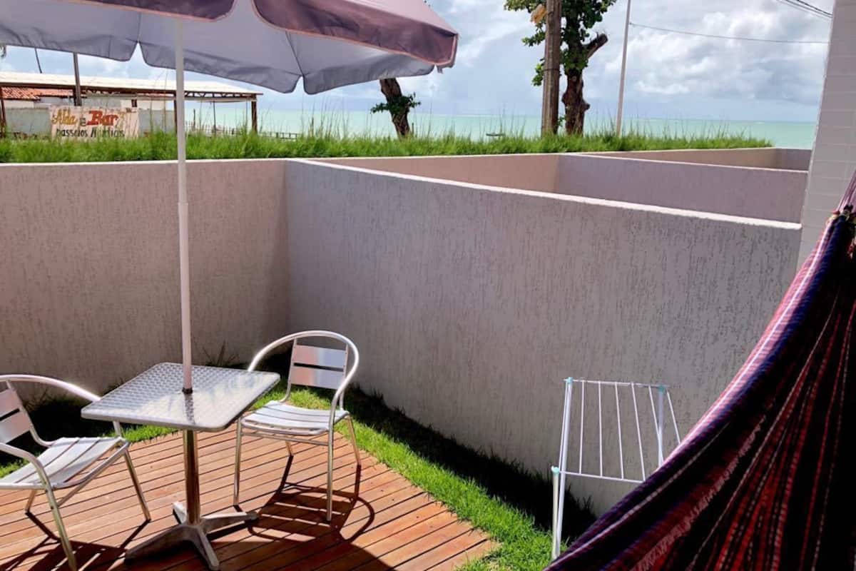 Une terrasse avec une table et des chaises, un hamac et une vue sur l’océan.