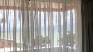 Una habitació amb cortines lleugeres, vista al mar i un ambient exterior.