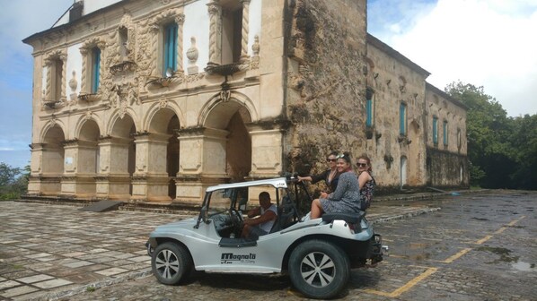 A vintage car parked in front of a historic building with arched windows and a stone facade.