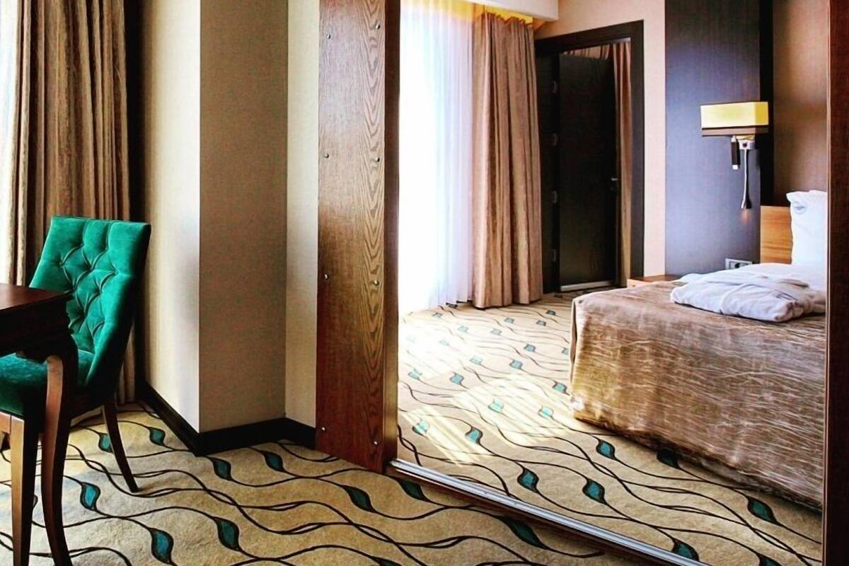 Una habitación de hotel con una cama, una silla, un espejo y una puerta.