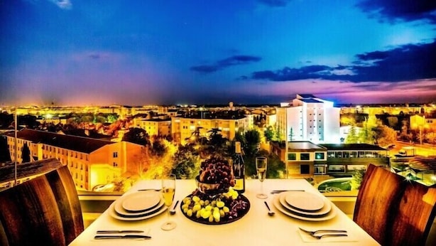 Mesa lista para cenar con vista a un paisaje urbano al atardecer.