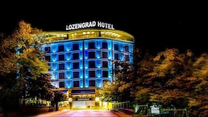 Exterior del hotel LoZengrad de noche, mostrando una estructura de varios pisos con ventanas iluminadas y un letrero destacado en la parte superior.