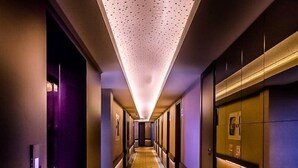 Un pasillo de hotel con suelo estampado, puertas y un techo con diseño perforado.