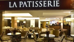 Un interior acogedor con sofás y mesas, una barra visible y un letrero que dice "LA PATISSERIE".