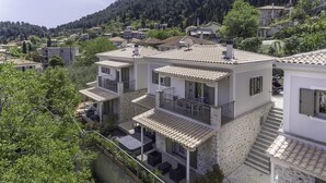 Un immeuble de deux étages doté d’une façade en pierre, de nombreux balcons et d’une terrasse aménagée avec du mobilier d’extérieur.