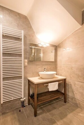 Un baño moderno con un lavamanos de pedestal grande, un espejo encima y un perchero para toallas.