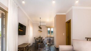 Un salon moderne comprenant un canapé, une table à manger avec des chaises, un téléviseur fixé au mur et un banc en bois.
