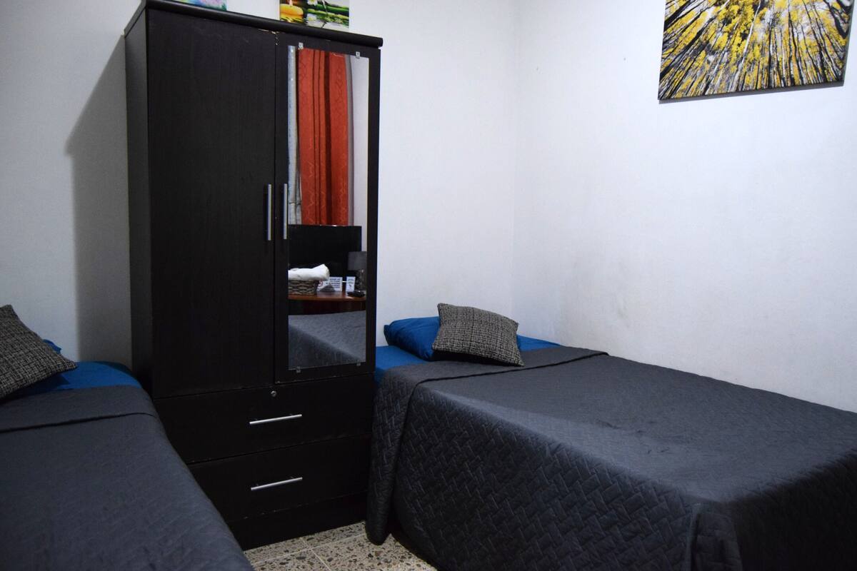 A bedroom with two single beds, a wardrobe, and a mirror.