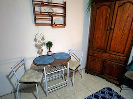 A dining area with a wooden table, two chairs, a dreamcatcher, and a cabinet.