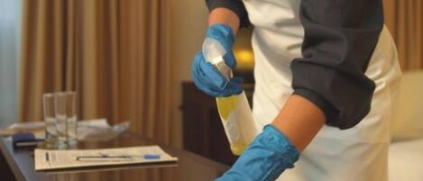 A person cleaning a table with a cloth and a spray bottle.