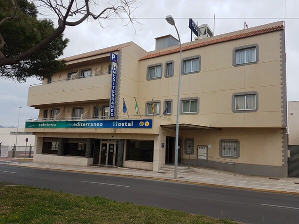 A building with a sign for 'Cafeteria Mediterraneo Hostel' and a parking sign. - Hostal Mediterráneo (El Ejido)