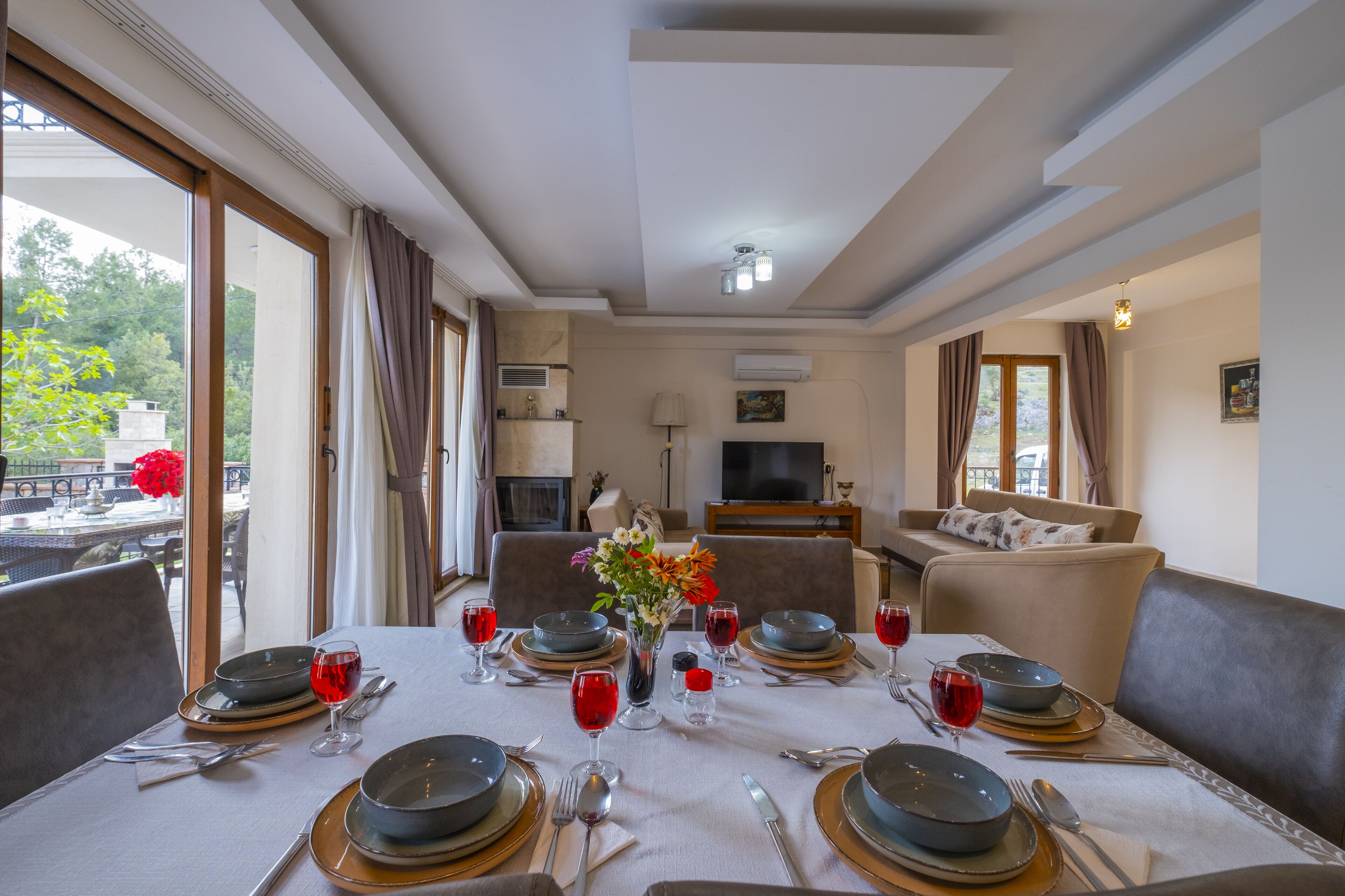 A dining area with a table set for four, a sofa, and a TV in the background.