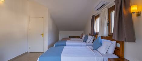 A hotel room with two beds, a wooden headboard, a nightstand, a wall-mounted air conditioner, and a window with curtains.