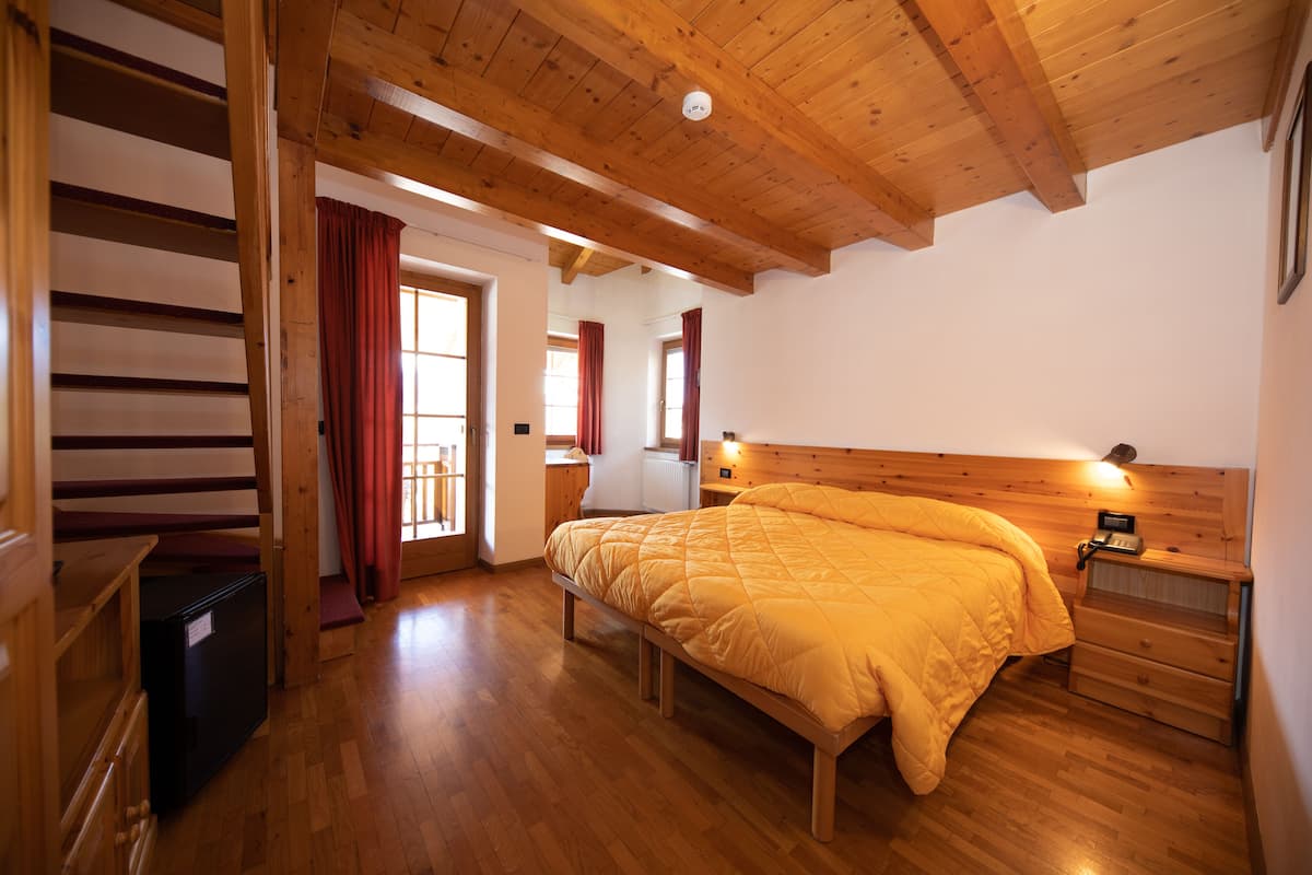 Un dormitorio con una cama de madera, una mesita de noche, un aparador y un banco empotrado.