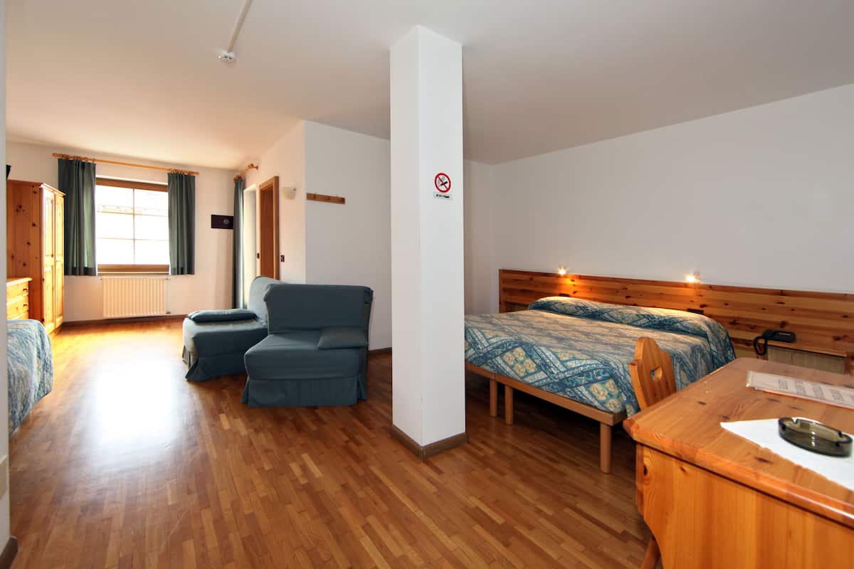 Una habitación con una cama, un escritorio, una silla y un sofá.