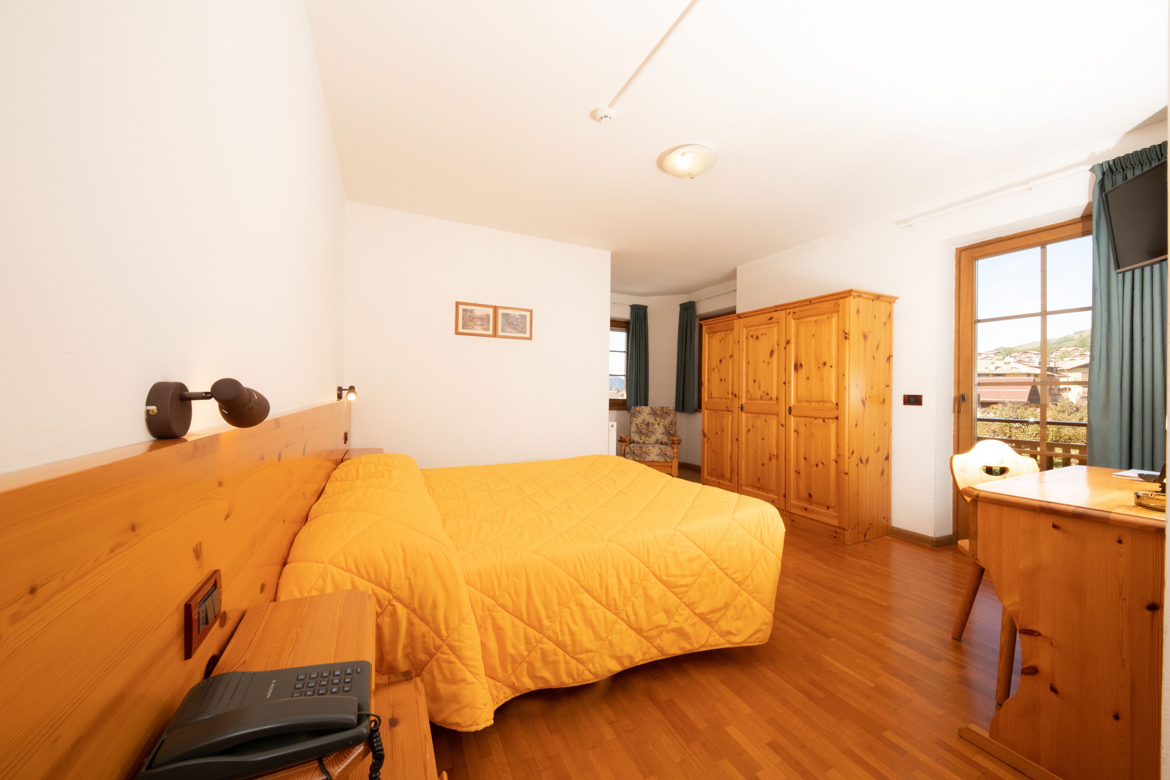 A bedroom with a wooden bed, a desk, and a wardrobe.
