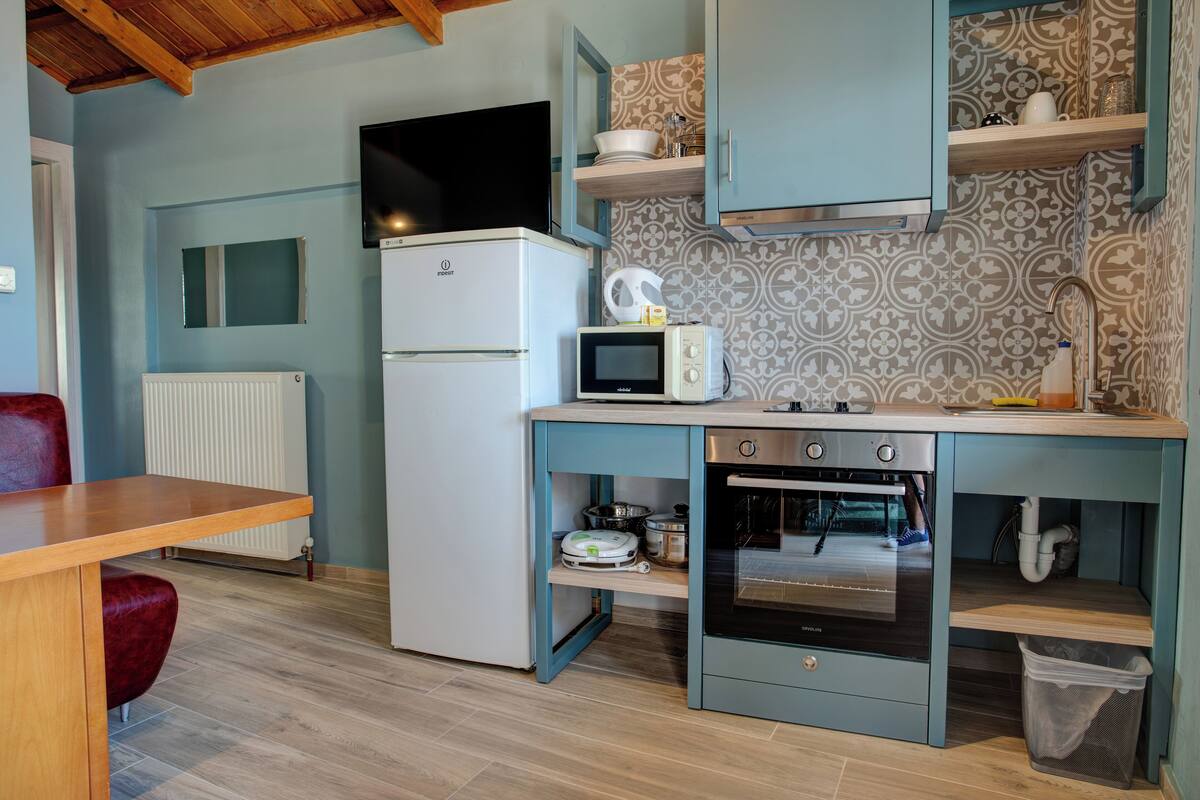 A compact kitchen with a built-in oven, microwave, and a small refrigerator.