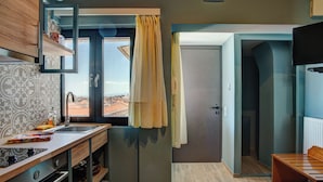 A compact kitchen with a window, a sink, and a built-in oven. - Heliotrope The Studios (Lesvos)