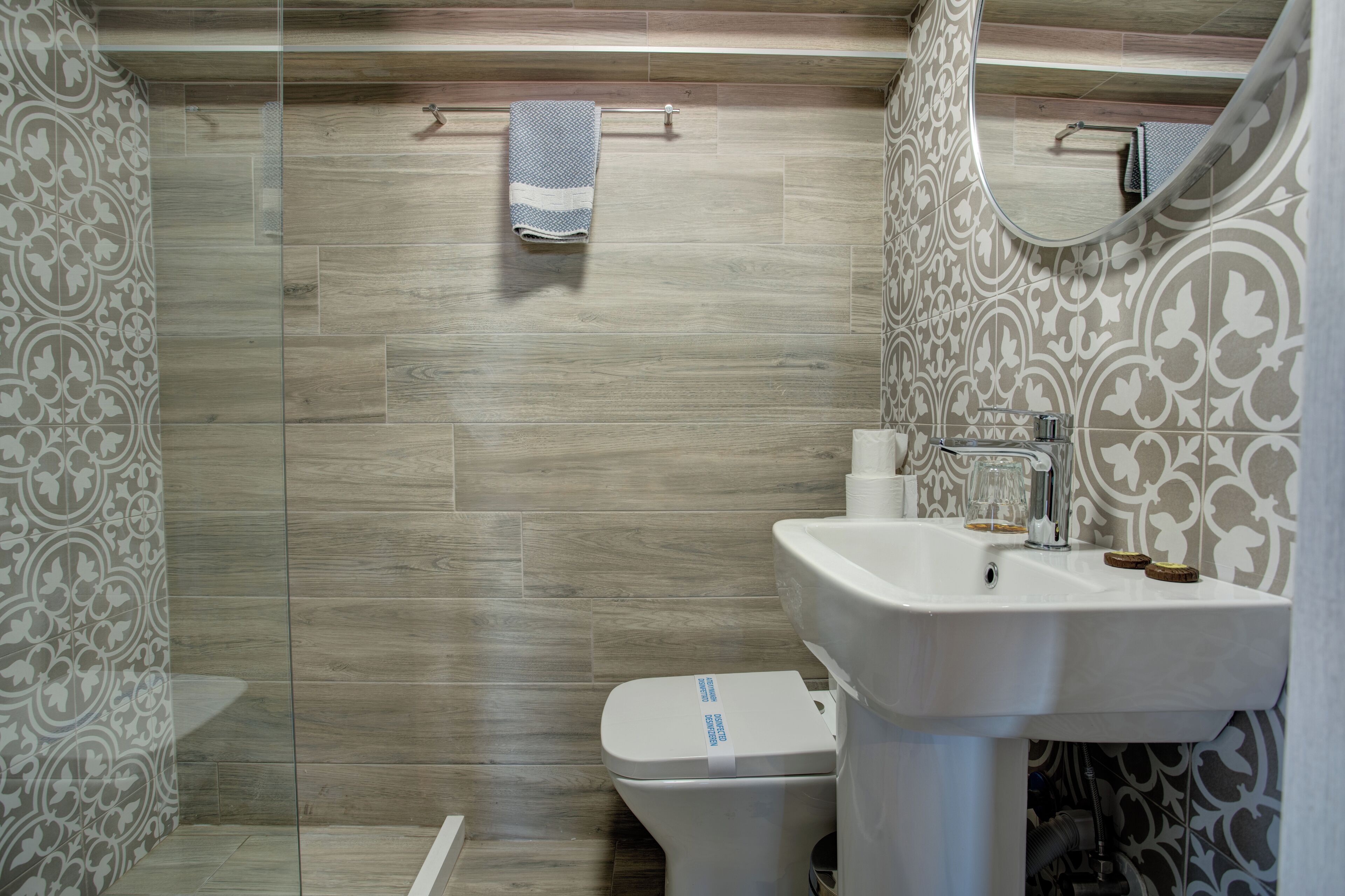 A bathroom with a modern design, featuring a toilet, sink, and mirror.