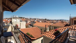 A balcony with a view of a cityscape, featuring terracotta rooftops and a clear blue sky. - Heliotrope The Studios (Lesvos)