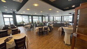 A spacious restaurant with high ceilings, large windows, and a variety of seating arrangements. - Berghotel Sankt Andreasberg (Braunlage)
