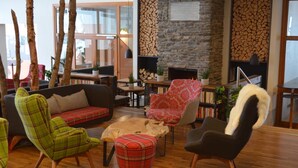 A cozy living room with a fireplace, a sofa, a coffee table, and a variety of chairs. - Berghotel Sankt Andreasberg (Braunlage)