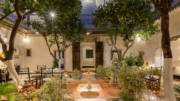 A courtyard with a central fountain, surrounded by tables and chairs, and adorned with plants and decorative lighting. - Riad Tchaikana (Marrakech)