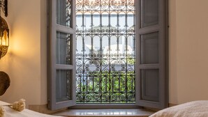 An open door with a wrought iron gate leading to a balcony with a view of greenery. - Riad Tchaikana (Marrakech)