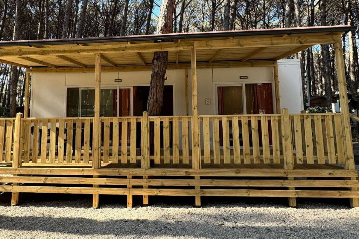 A wooden cabin with a covered porch, surrounded by trees.