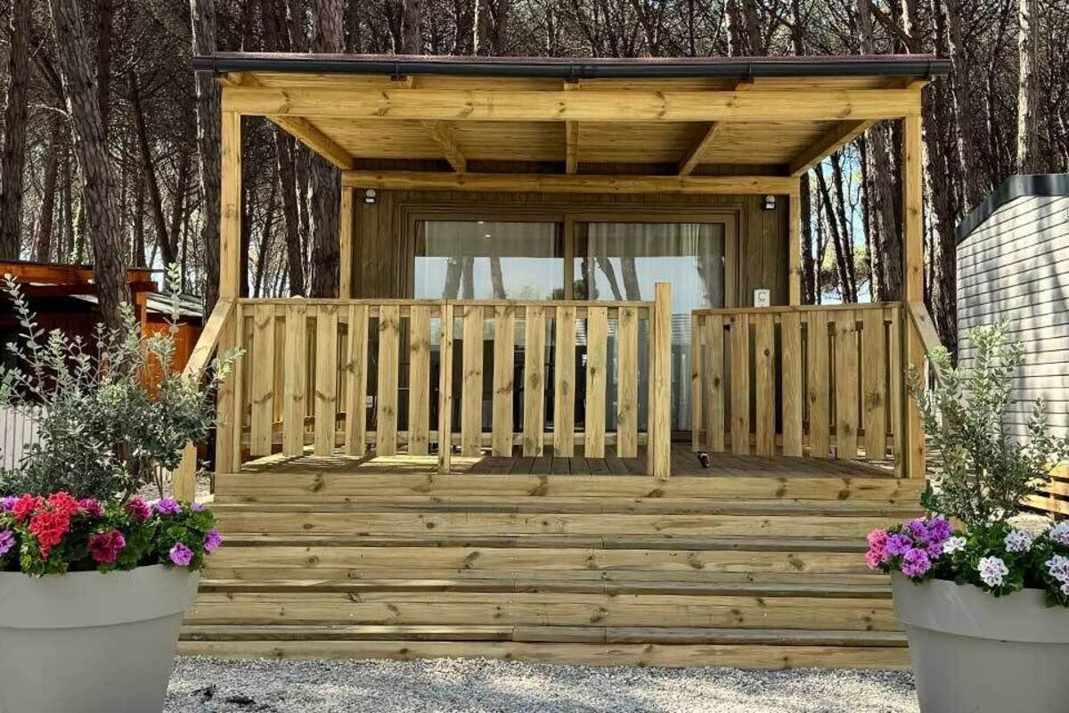 A wooden cabin with a porch, surrounded by trees.