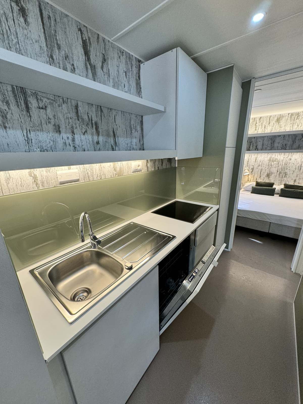 A modern kitchen with two sinks, a dishwasher, and a marble backsplash.