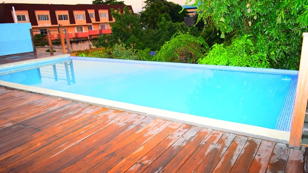 A rectangular swimming pool with a wooden deck surrounding it. - New Kingston Luxury Apt The Bromptons (Kingston)