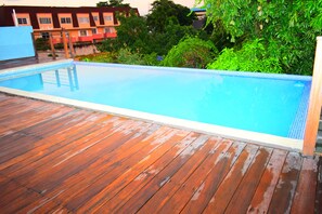 Une piscine rectangulaire entourée d’une terrasse en bois.