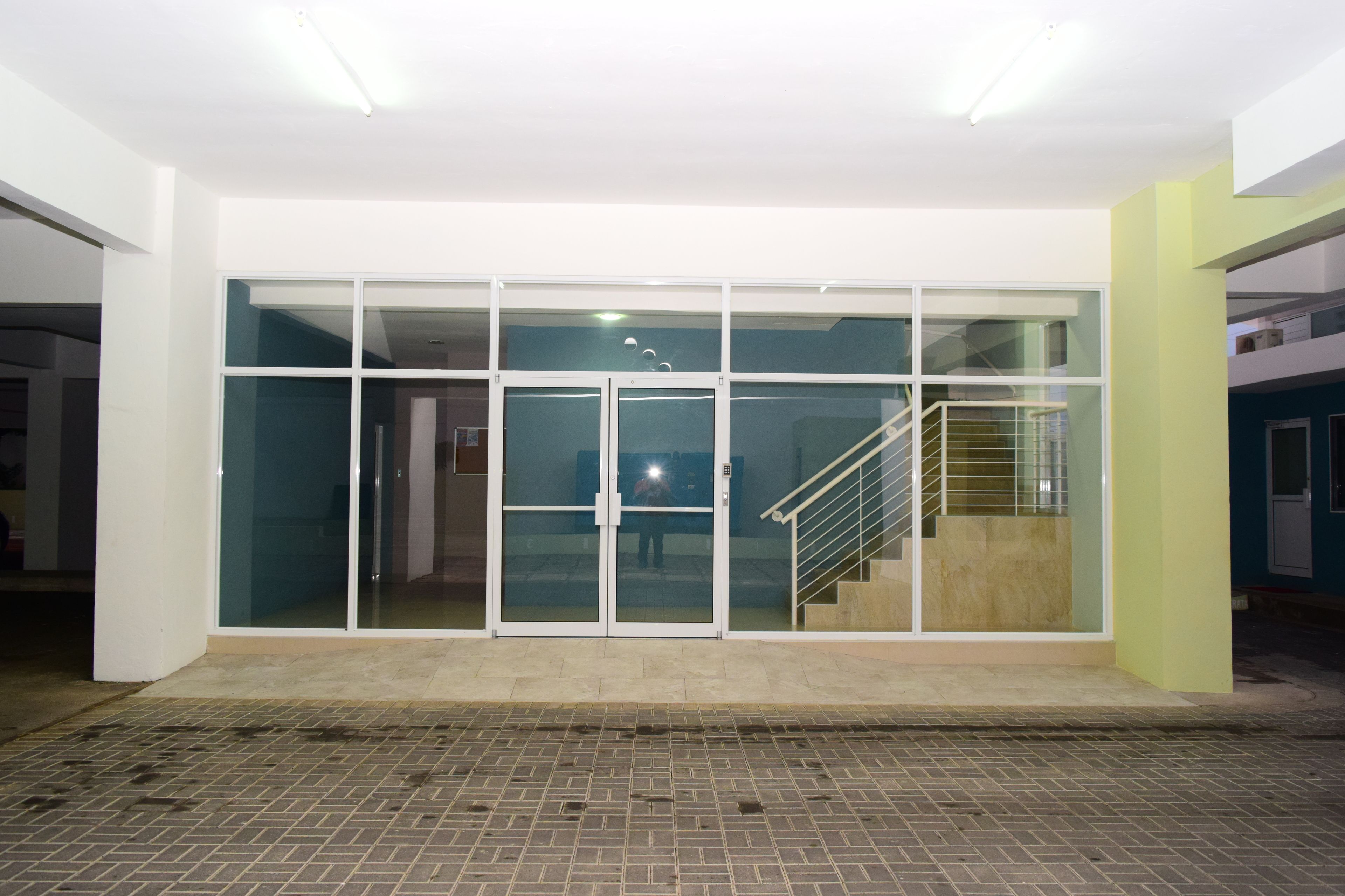 A modern building with a glass entrance, a staircase, and a tiled floor.