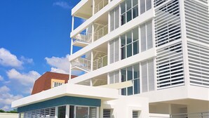 A modern multi-story building with balconies, large windows, and a blue accent wall. - New Kingston Luxury Apt The Bromptons (Kingston)