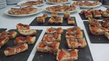 A buffet table with various food items, including pizzas and bread topped with ingredients.