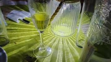 Una mesa con mantel verde, un vaso con líquido amarillo y una botella.