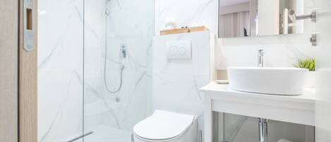 Un bagno moderno con doccia vetrata, un water bianco e un lavandino con specchio sopra.