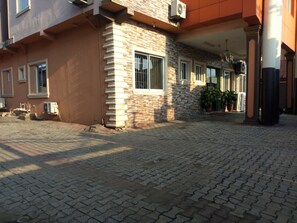 A building with a brick facade, a paved entrance, and potted plants. - Suncity Hotel (Lagos)
