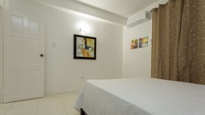 A bedroom with a bed, a door, and two wall-mounted paintings. - New Kingston Premium Guest Apartment (Kingston)