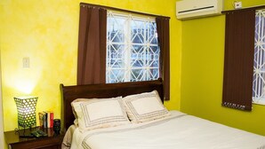 A bedroom with a bed, a nightstand, a lamp, and a window with curtains. - New Kingston Guest Apt at The Stadium (Kingston)