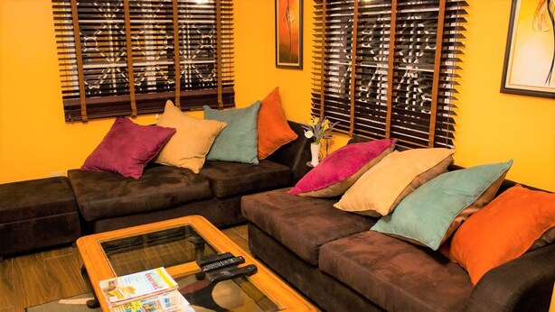 A living room with a sectional sofa, a glass coffee table, and a small side table. - New Kingston Guest Apt at The Stadium (Kingston)
