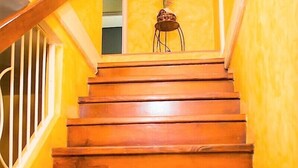 A wooden staircase with a railing, leading to a room with yellow walls and a small table with a vase. - New Kingston Guest Apt at The Stadium (Kingston)